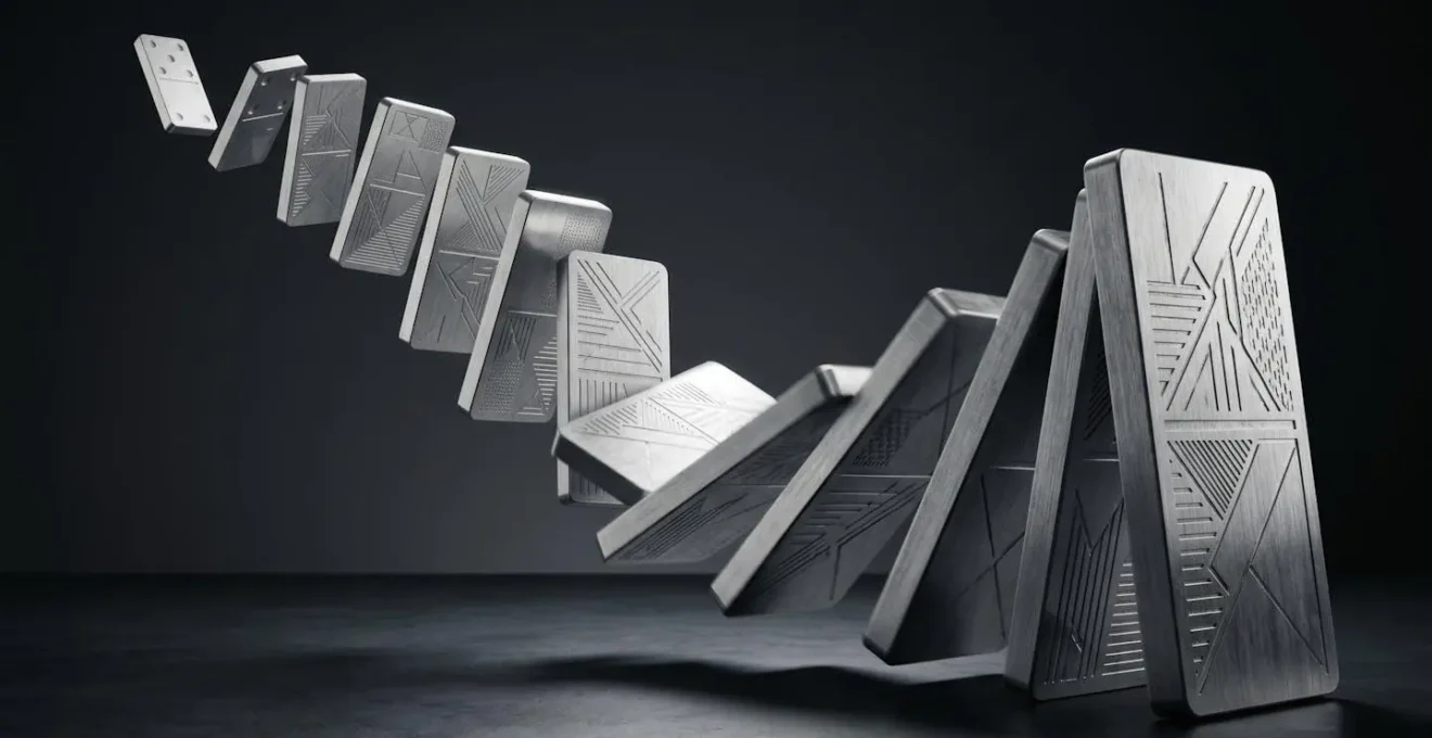 A visual metaphor of a cascade failure, shown as a line of falling dominoes.