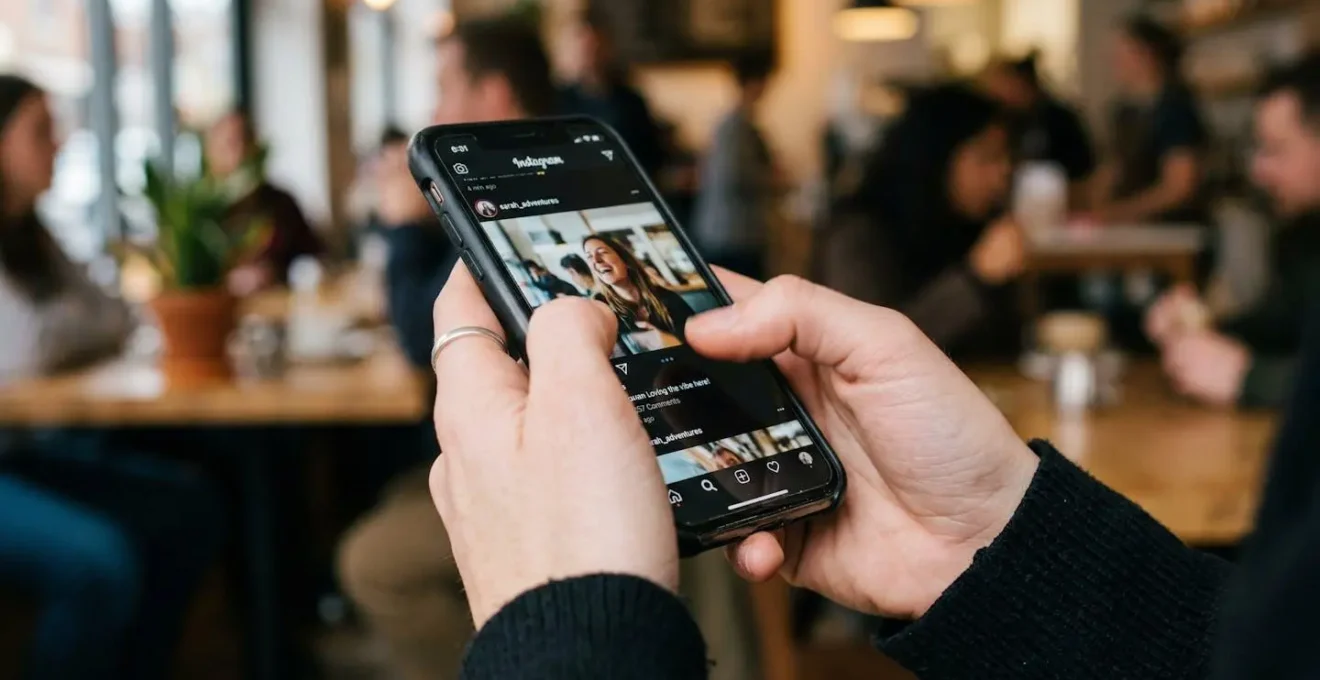 A person scrolls through content on a smartphone in a casual setting with natural lighting